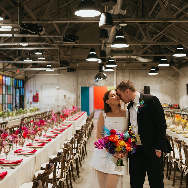A bride and groom with tables in Garage B, a modern industrial event venue at the Charles River Speedway.